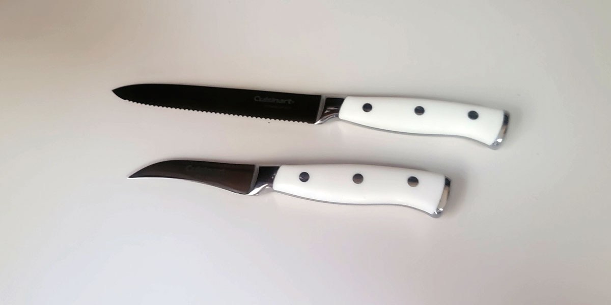 Two Cuisinart knives with white handles displayed horizontally on counter Two Cuisinart knives with white handles displayed horizontally on counter