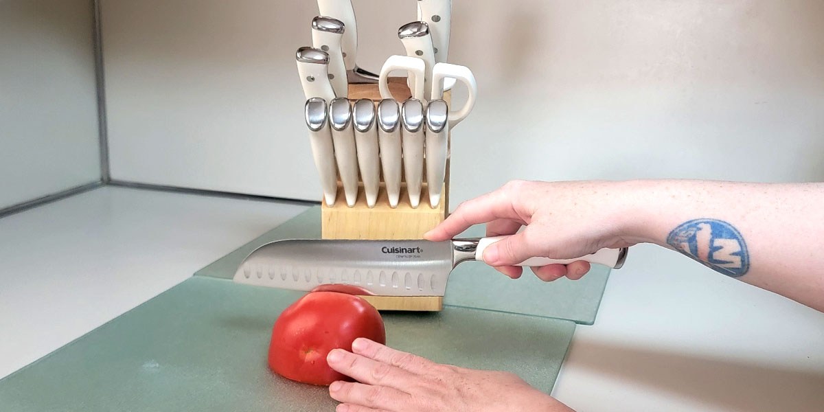 Hand using Cuisinart knife to slice tomato Hand using Cuisinart knife to slice tomato