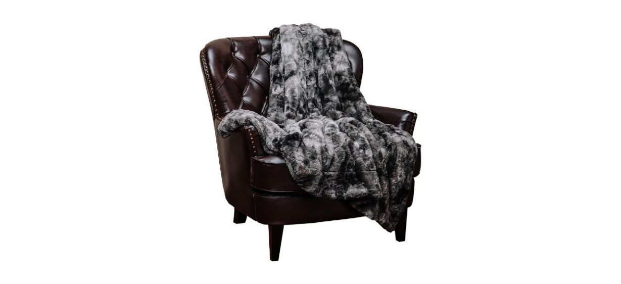 A brown leather chair with a very furry gray blanket on it