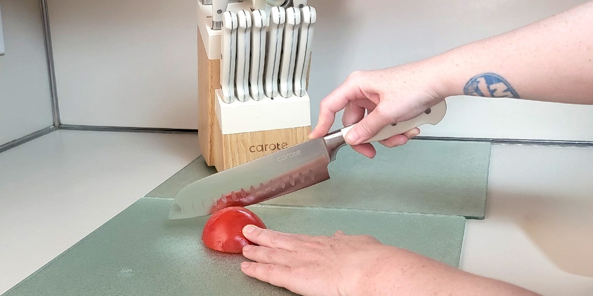 Hand using Carote 14-Piece Forged Knife Set knife to slice tomato